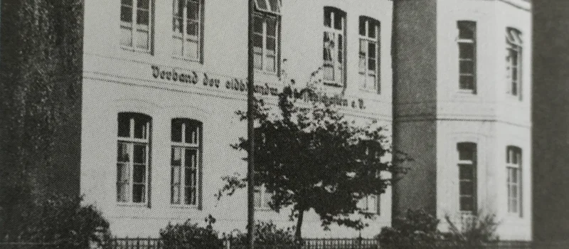 Historische Schwarz-Weiß-Aufnahme eines mehrgeschossigen Gebäudes mit Schriftzug an der Fassade. Das Bild begleitet den Meilenstein zur Ausweitung des Verbandsgebietes und zu neuen Strukturen nach dem Zweiten Weltkrieg.