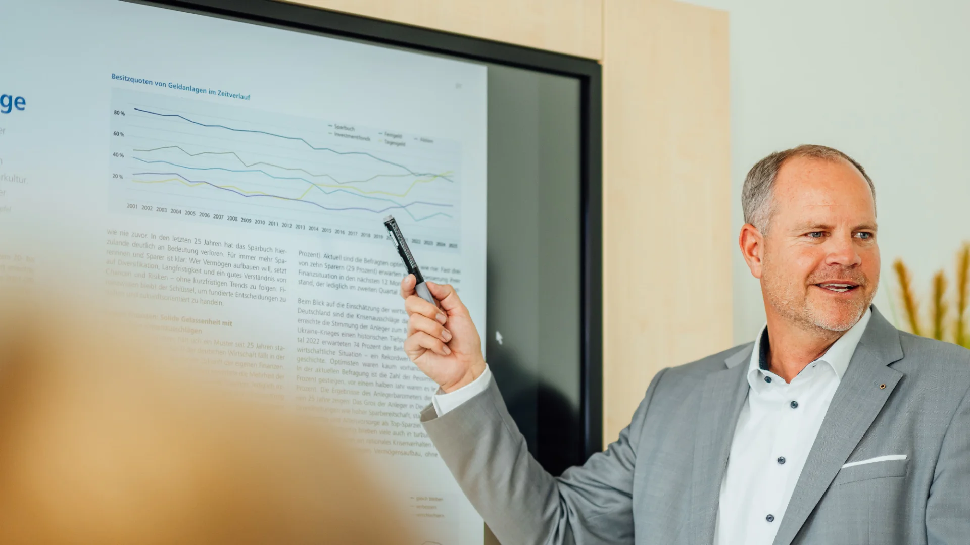 Ein Mann in Geschäftskleidung zeigt mit einem Stift auf eine Präsentation mit Diagramm und Fachtext. Das Bild steht für fachliche Beratung und analytische Entscheidungsunterstützung beim Genossenschaftsverband Weser-Ems.