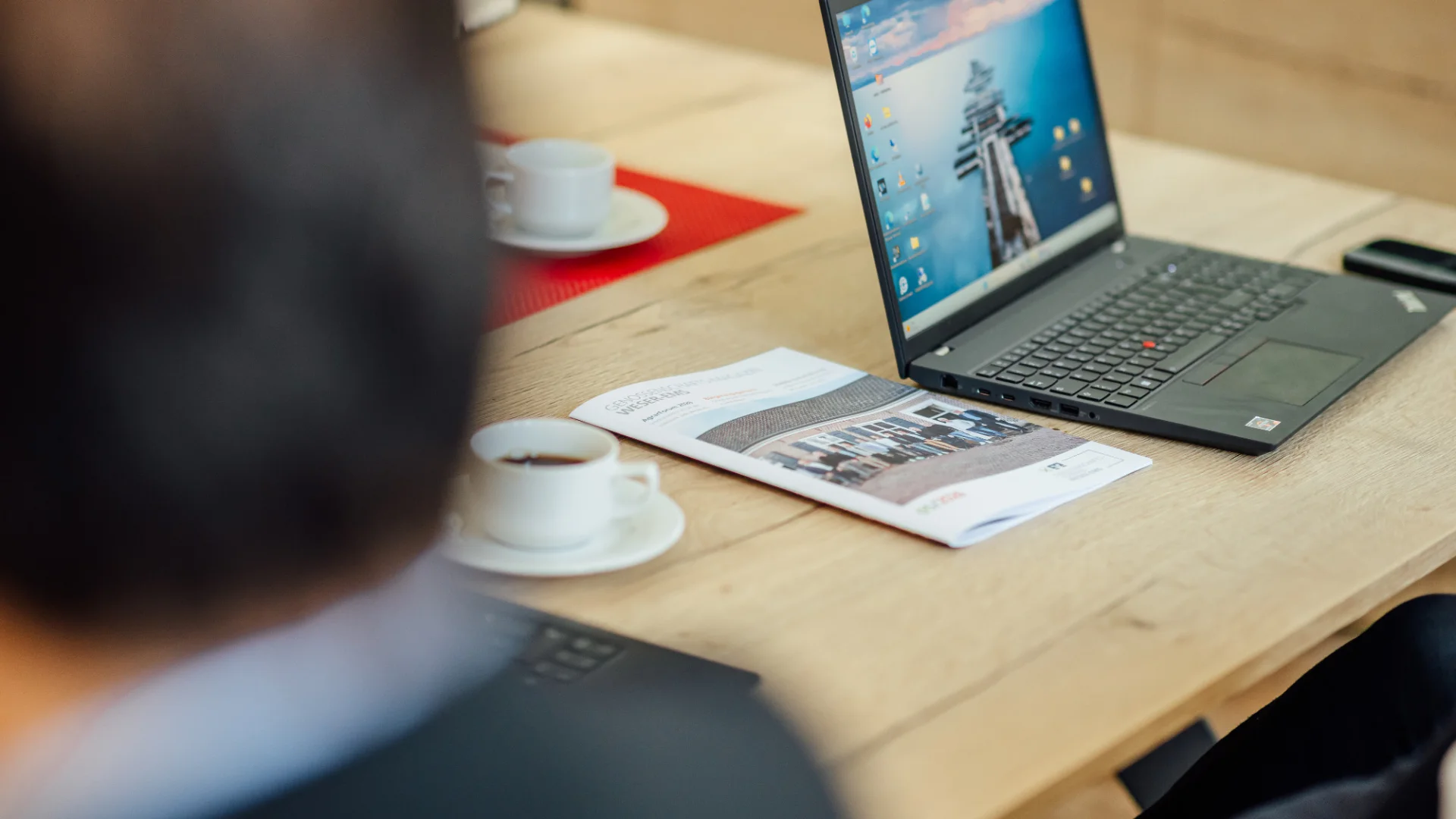 Ein geöffneter Laptop, eine GVWE-Broschüre und Kaffeetassen liegen auf einem Besprechungstisch. Das Bild steht für persönliche Gründungsberatung und die fachliche Begleitung beim Aufbau einer Genossenschaft.