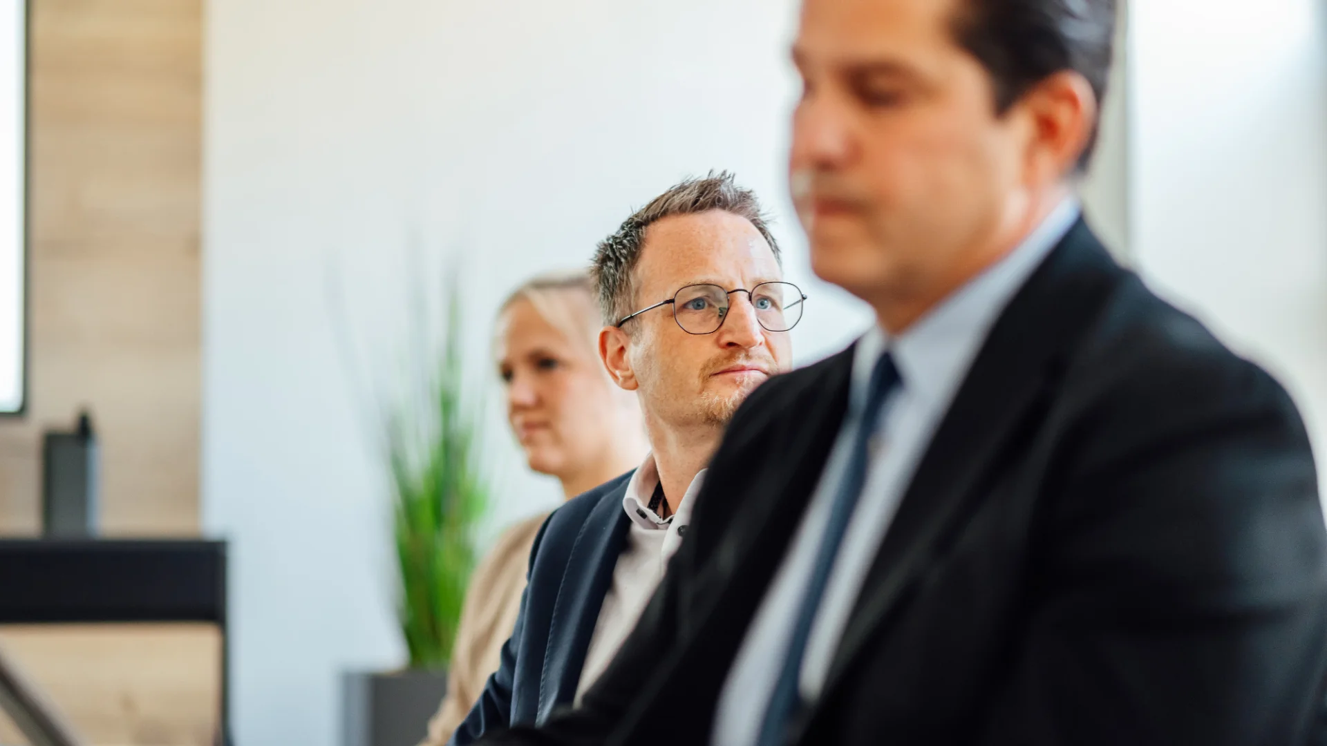 Mehrere Personen sitzen in einem Besprechungsraum und hören einem Gespräch zu. Das Bild steht für fachlichen Austausch, Gremienarbeit und die Interessenvertretung der Mitglieder des GVWE.