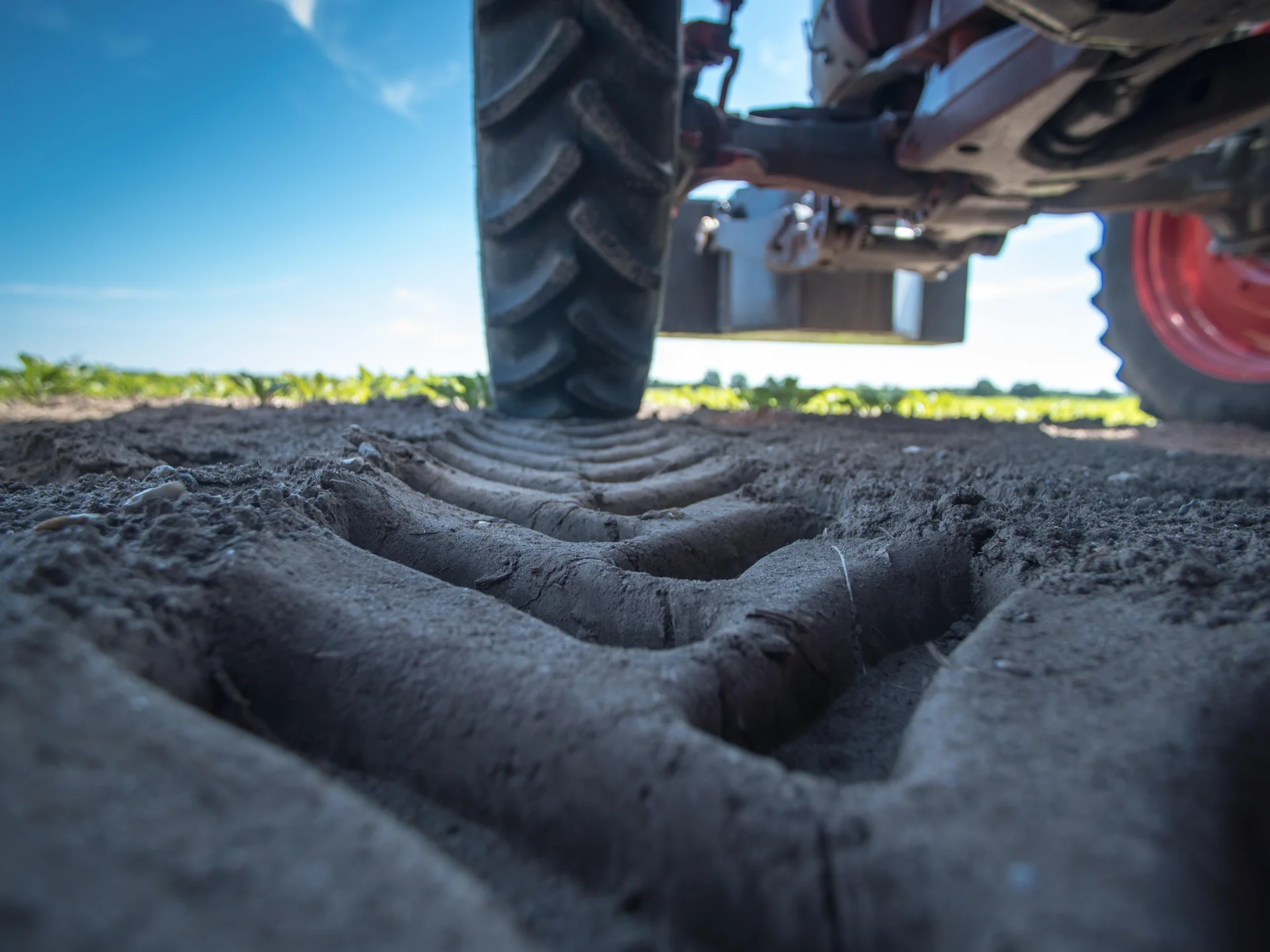 Nahaufnahme eines Traktorreifens, der tiefe Spuren im Ackerboden hinterlässt. Das Bild steht für landwirtschaftliche Produktion und Warengenossenschaften als starke Handelspartner in Weser-Ems.