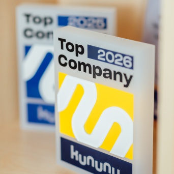 Zwei Auszeichnungen mit der Aufschrift „Top Company 2026“ von kununu stehen auf einem Tisch.